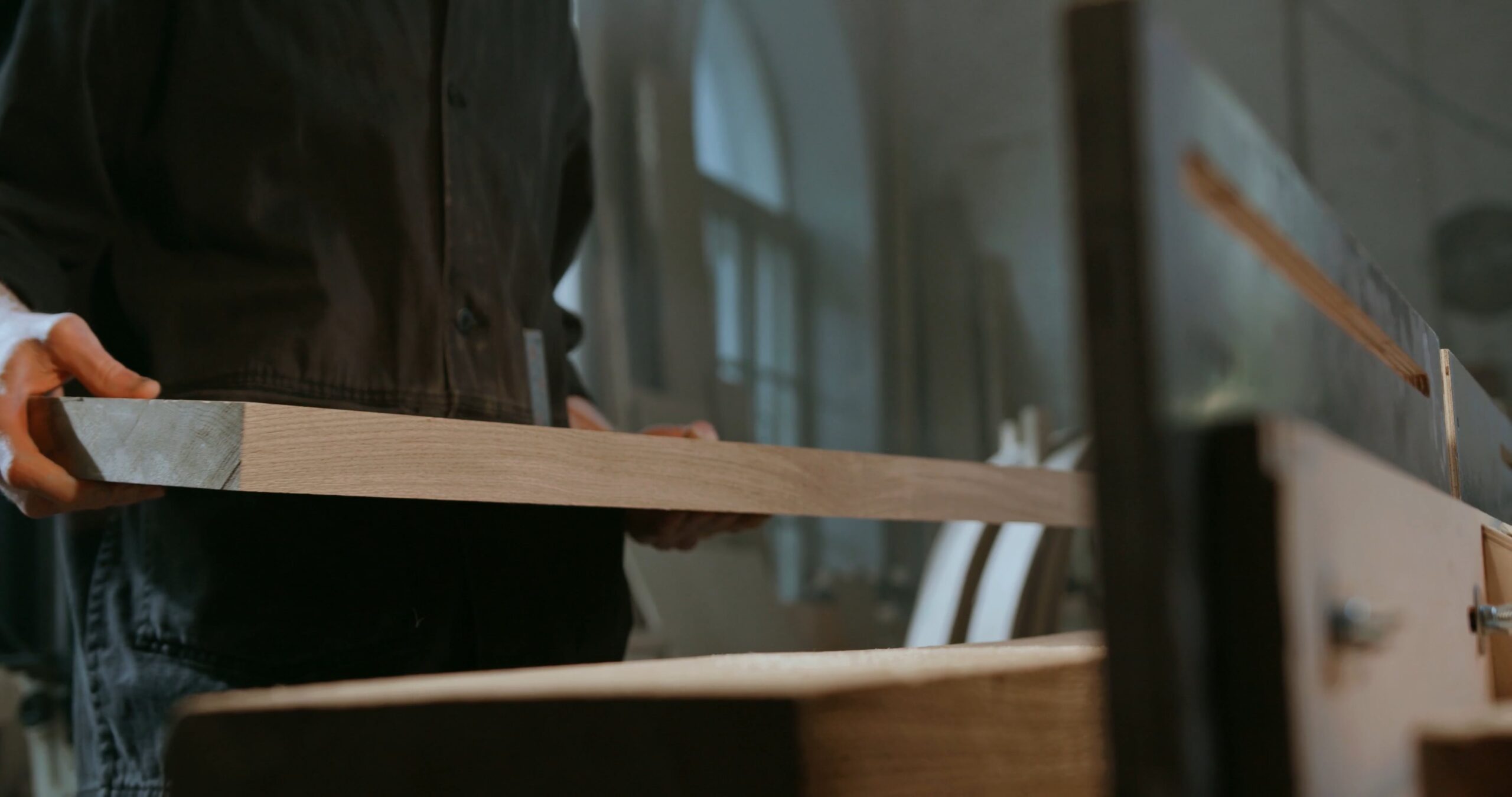 Carpintero con una tabla de madera cortada en el taller de Maderas Lamelas
