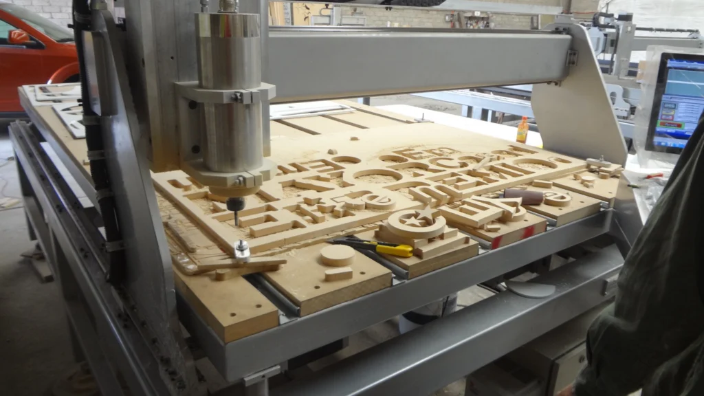 Letras y formas fresadas en un tablero de MDF sobre la mesa de un pantógrafo CNC